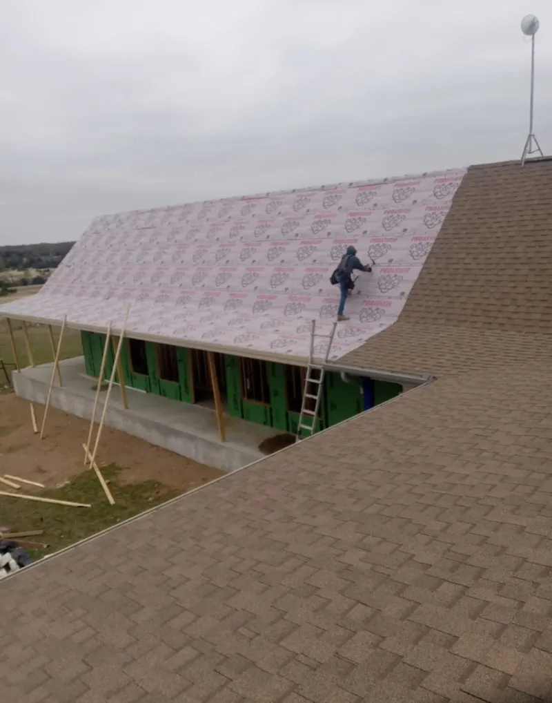 Worker preparing underlayment for a metal roof installation in Denton